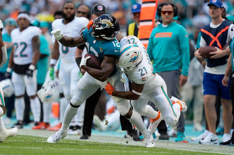 Miami Dolphins safety Jordan Poyer (21) tackles Jacksonville Jaguars wide receiver Devin Duvernay (12) during the second half of an NFL football game, Sunday, Sept. 8, 2024, in Miami Gardens, Fla. (AP Photo/Rebecca Blackwell)