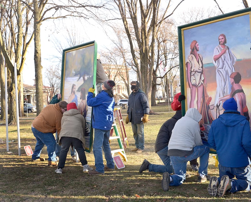 Volunteers lift to install 2 of the 16 paintings depicting the life of Christ Saturday in Ottawa’s Washington Square.The 4-foot by 7-foot paintings. The Ottawa Freedom Association has erected the paintings each year since 1992 after winning a lengthy court battle.