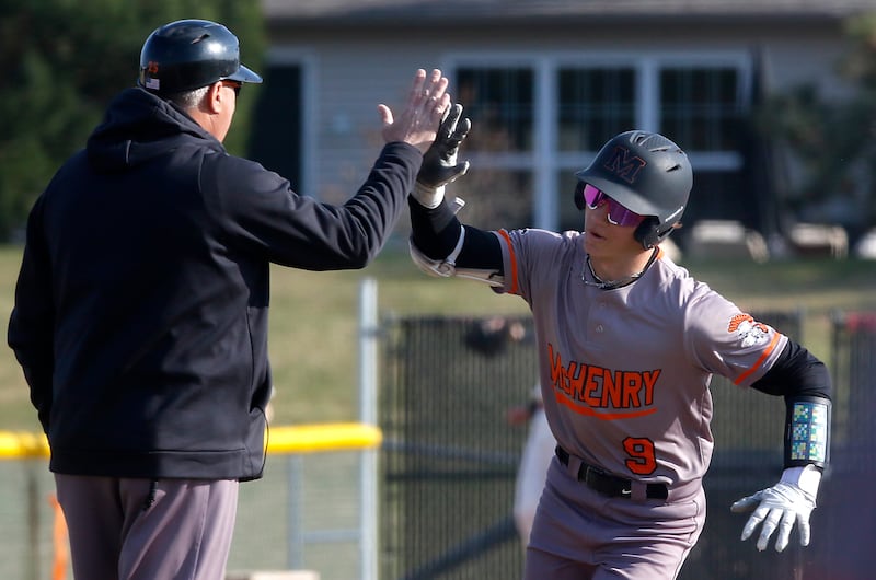McHenry Head Baseball Coach Brian Rockweiler high fives McHenry's Carver Cohn after he hits a grand slam home run during a Fox Valley Conference baseball game against Huntley on Friday, April 11, 2025, at Huntley High School.