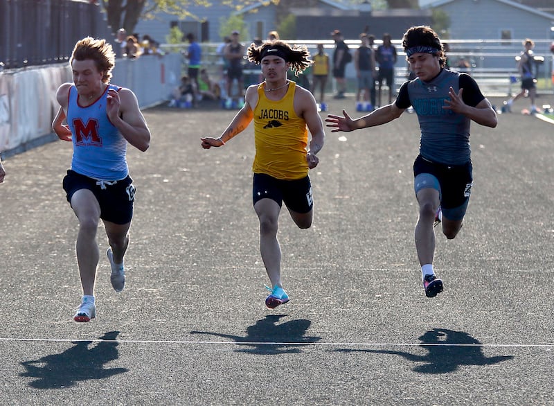 Marian Central ’s Wilson Jakubowicz, (left) Jacobs’ Kieran Nally (center) and Woodstock North’s Adan Castaneda race to the finish line in the 100 meter dash on Thursday, April 23, 2026, during the McHenry County Track and Field Meet at McCracken Field in McHenry.