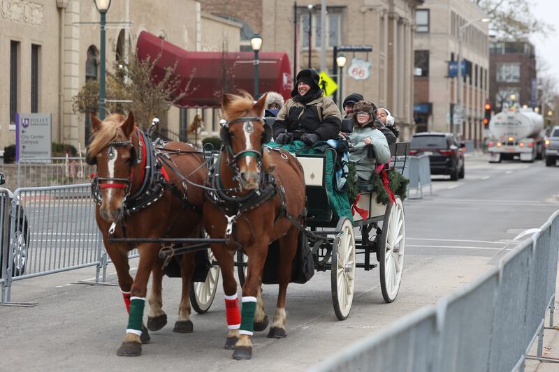 A group takes a horse drawn carriage ride down North Ottawa Street at the Joliet Light Up the Lights Holiday Festival on Friday, Nov. 29, 2024.
