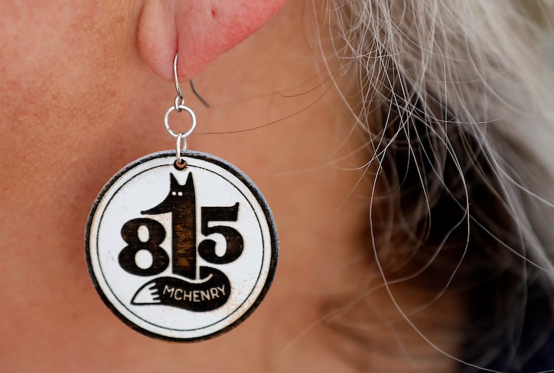 Amy Humbracht the manager of the McHenry Riverwalk Shoppes sports 815 earrings on Friday, Aug.15, 2025, during McHenry’s 815 Day.