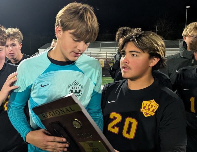 Richmond-Burton goalkeeper Easton Wold (left) and Luis Munoz hold the championship plaque after the Rockets beat Chicago Math and Science Academy 3-0 in the Class 1A Richmond-Burton Regional final Thursday, Oct. 23, 2025, in Richmond.