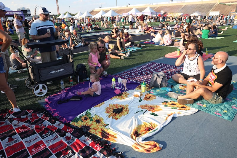 A group of friends find a spot on the field to relax and enjoy the music at the Taste of Joliet on Friday, June 21, 2024 at Joliet Memorial Stadium.