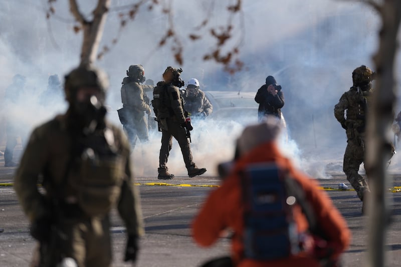 Federal immigration officers deploy tear gas at protesters after a shooting Saturday, Jan. 24, 2026, in Minneapolis. (AP Photo/Abbie Parr)