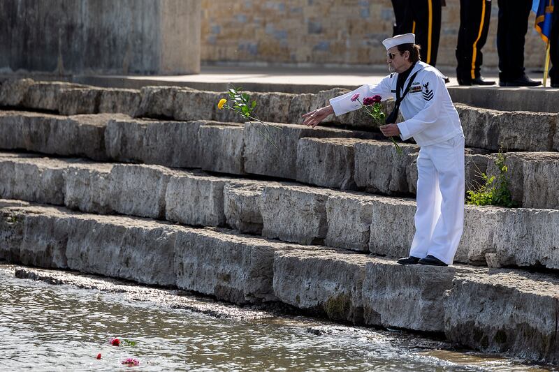 Dave Devine throws flowers into the Rock River in recognition of Memorial Day Monday, May 26, 2025, to honor those who died at sea.