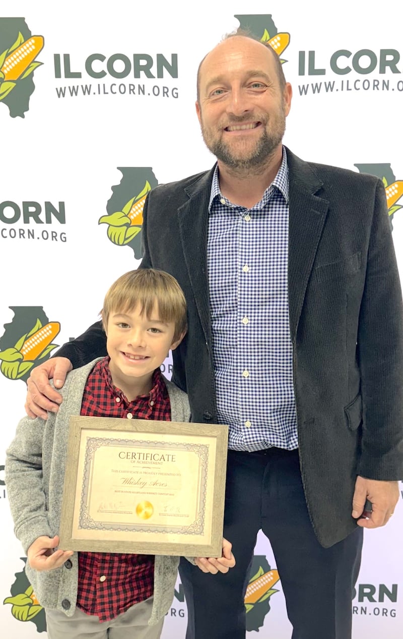 Nick Nagele, co-founder, distiller and farmer at Whiskey Acres Distilling Company, and his son, Gunnar, show the Best-in-State for Illinois award the DeKalb business earned in the Heartland Whiskey Competition. Whiskey Acres was recognized for its accomplishment during the Illinois Corn Growers Association’s annual meeting.