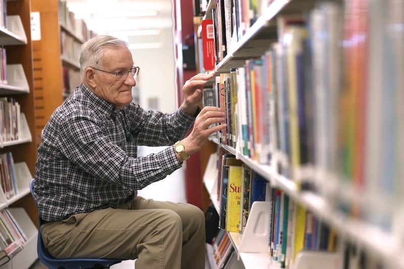 Longtime DeKalb Public Library volunteer Paul Mandigo, 83, straightens up books on the shelves Wednesday, March 25, 2026, at the library in DeKalb.