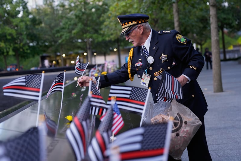 Sam Pulia places flags on names inscribed in the 9/11 Memorial before the start of a ceremony commemorating the 24th anniversary of the Sept. 11, 2001, attacks, Thursday, Sept. 11, 2025, in New York.  (AP Photo/Seth Wenig)