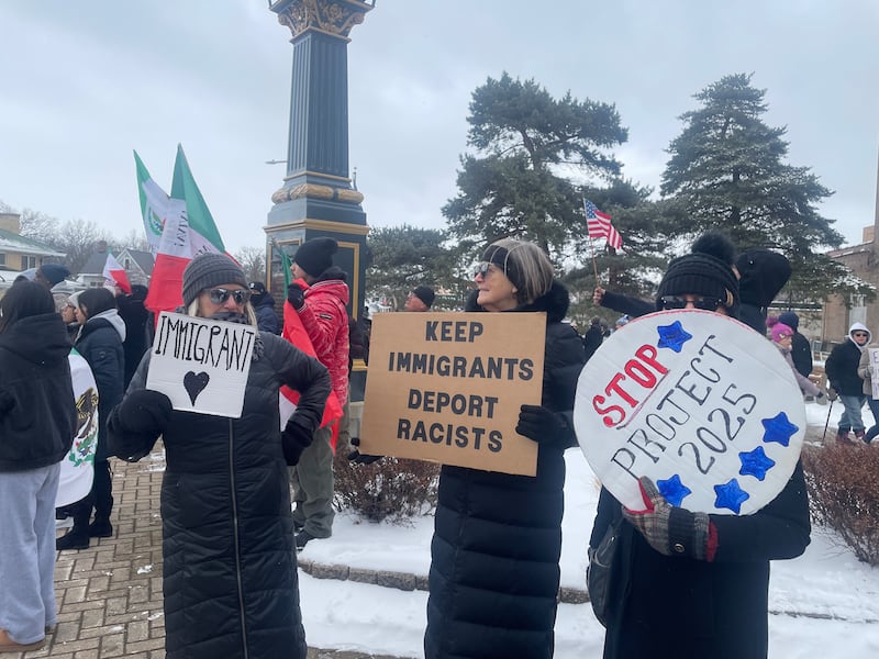Candy Smith (left to right), Joan Lanning and Sue Willey hoist up signs Sunday, Feb. 16, 2025, at Peace Corner in DeKalb in protest of the federal administration's immigration policies.