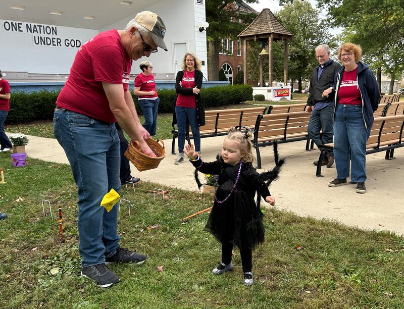 Emersyn Stauffer, 3, tosses a bean bag at a target at one of the kid's game offered by the Evangelical Church of Mt. Morris during Let Freedom Ring's Fall Family Festival on Sunday, Oct. 12, 2025.  The downtown event also included a car show and trunk or treat.
