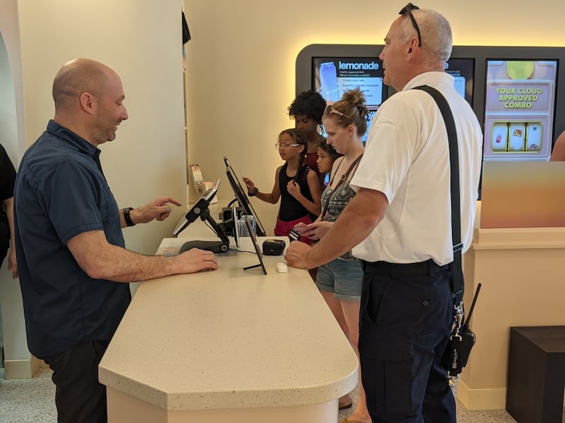 Candy Cloud owner Scott Bedows, left, takes an order from Oswego Fire Protection District Lt. Kris Kearns, right, during the store's soft opening on Tuesday, July 1.