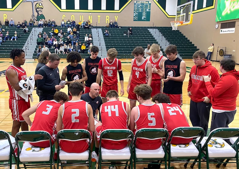 Streator boys basketball head coach Beau Doty (kneeling at center) instructs his Bulldogs during a timeout Tuesday, Jan. 28, 2025, at Coal City.