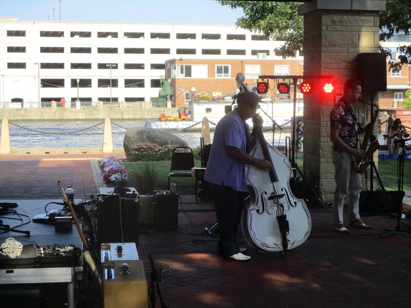 Michael "Q" Quiroz plays bass with Mondo Cortez and the Chicago Blues Angels at the Joliet Blues Festival as a barge on the Des Plaines River passes by Billie Limacher Bicentennial Park. Aug. 9, 2025