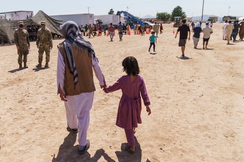 FILE - A man walks with a child through Fort Bliss' Doña Ana Village where Afghan refugees are being housed, in New Mexico, Friday, Sept. 10, 2021.   (AP Photo/David Goldman, File)
