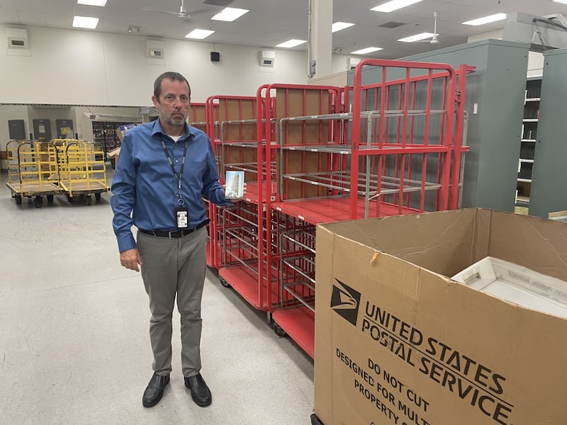 The postcard in Ottawa Postmaster Mark Thompson's hands arrived Friday, Aug. 8, 2025. It was postmarked in 1953. Thompson has a theory for why it took 72 years for the card to arrive from New York City.