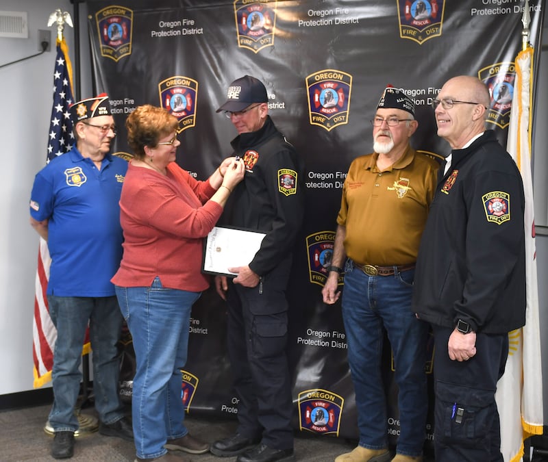 Lyn Hunter, wife of Oregon Firefighter/EMT Greg Hunter, pins his VFW EMT of the Year medal to his chest during a presentation at the Oregon VFW Post #8739 on Monday, March 3, 2025. Pictured, left to right, are: VFW Senior Vice Commander Lee Ossmann, Lyn and Greg Hunter, Assistant VFW Quartermaster Robert Coulter and Oregon Fire Chief Michael Knoup.