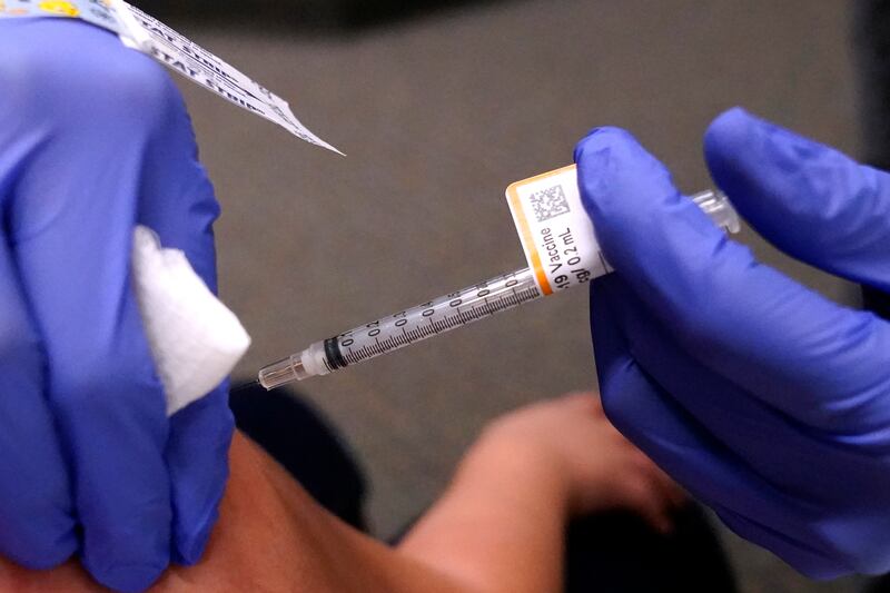 An eight-year-old child receives a second dose of the Pfizer COVID-19 vaccine at Northwest Community Church in Chicago, Saturday, Dec. 11, 2021. Pfizer is adding an extra dose of its COVID-19 vaccine for babies and preschoolers enrolled in a study of the shots. Pfizer and its partner BioNTech announced, Friday, Dec. 17, they were adding a third dose to the study after a preliminary analysis found 2- to 4-year-olds didn't have as strong an immune response as expected.