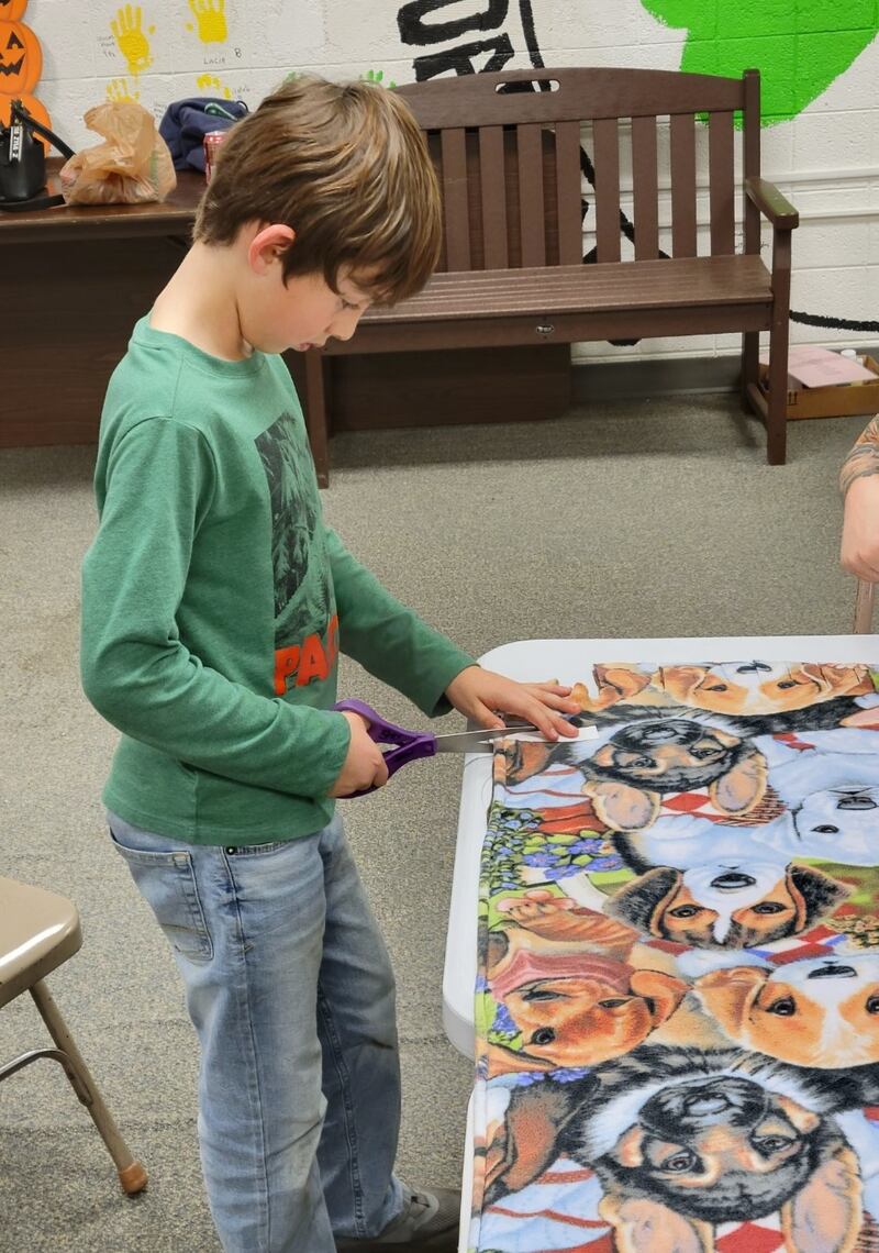 Pictured is Luis Smith cutting one of the tie blankets during the workshop.
