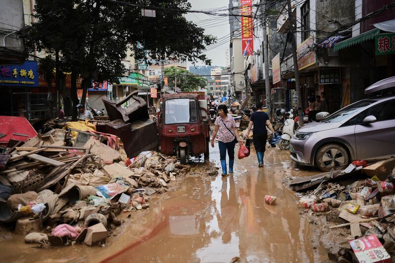 FILE -In this photo released by Xinhua News Agency, residents wade through debris along a flood-hit street after waters from a river overwhelmed towns following days of heavy rain, in Huaiji County, south China's Guangdong Province on June 19, 2025. (Deng Hua/Xinhua via AP, File)