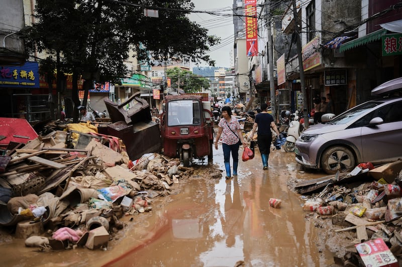 FILE -In this photo released by Xinhua News Agency, residents wade through debris along a flood-hit street after waters from a river overwhelmed towns following days of heavy rain, in Huaiji County, south China's Guangdong Province on June 19, 2025. (Deng Hua/Xinhua via AP, File)
