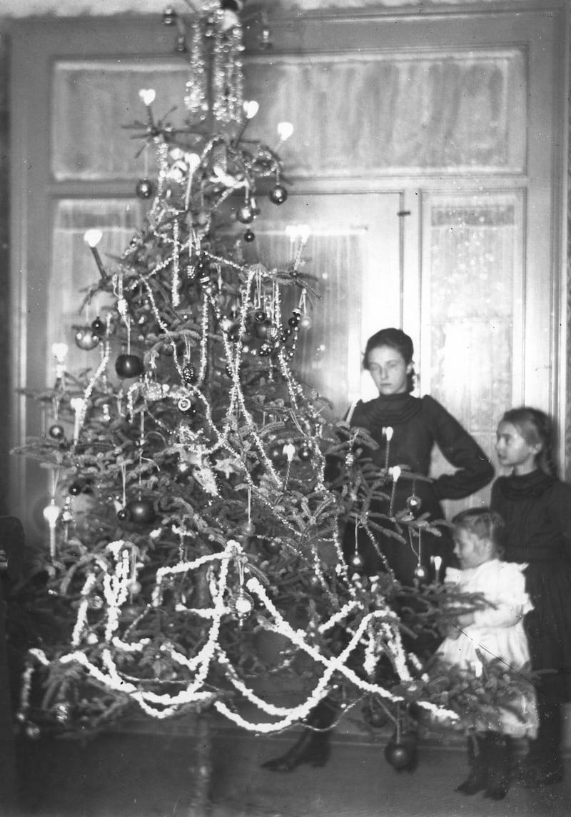 My grandmother's cousins, Florence (1902-1924), Olive (1906-1971), and little John (1910-1977) Minnich (in white dress) around a Christmas tree lit with lighted candles, probably at their aunt’s North Adams Street, Oswego, home about 1913. The hazardous practice of candle-lit Christmas trees caused amazingly few fires until electric Christmas tree lights eliminated the danger.