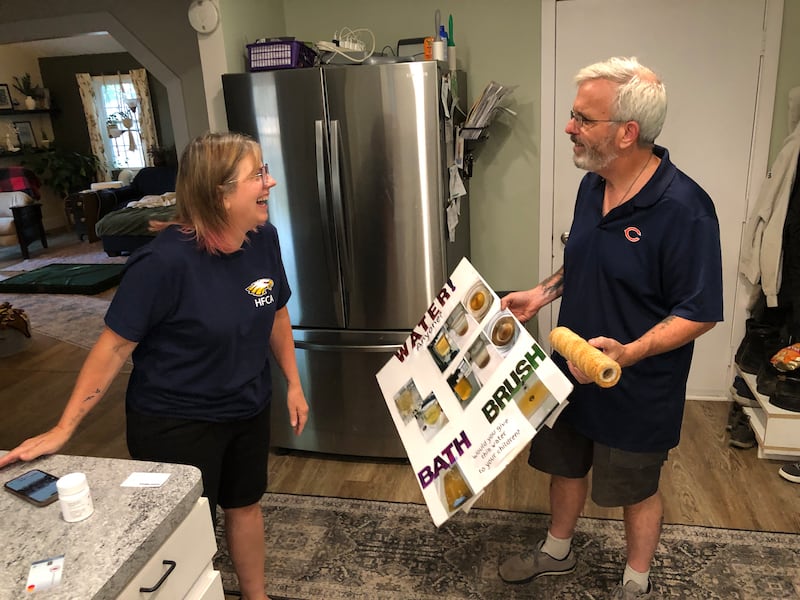 Laura Clark, left, with Mike Clark on Friday, May 15, 2025, at their Eastwood Manor home. Laura made this poster when she spoke against Aqua Illinois's request for a rate increase last year.