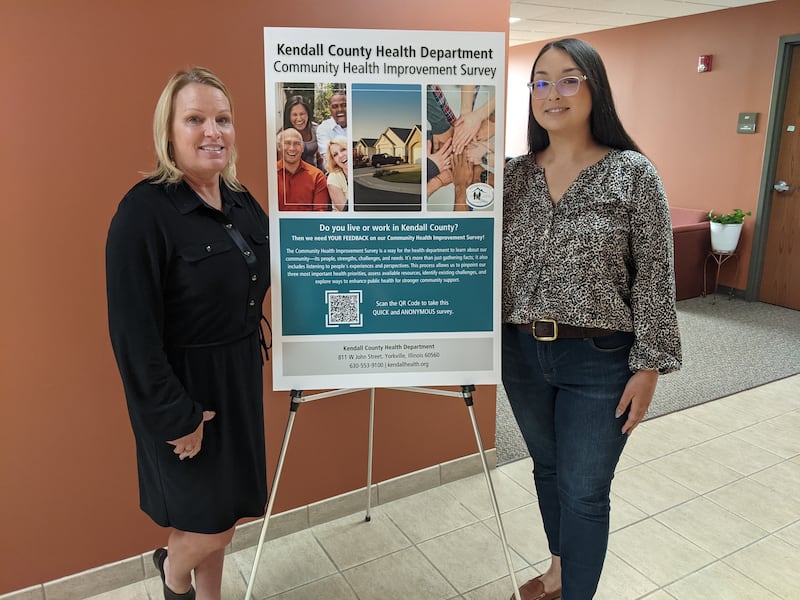 Kendall County Health Department Executive Director RaeAnn VanGundy, left, and Kendall County Health Department Assistant Executive Director Rachael Hendrickson, right, stand next to a sign about the department's community health improvement study on Friday, Sept. 19, 2025.