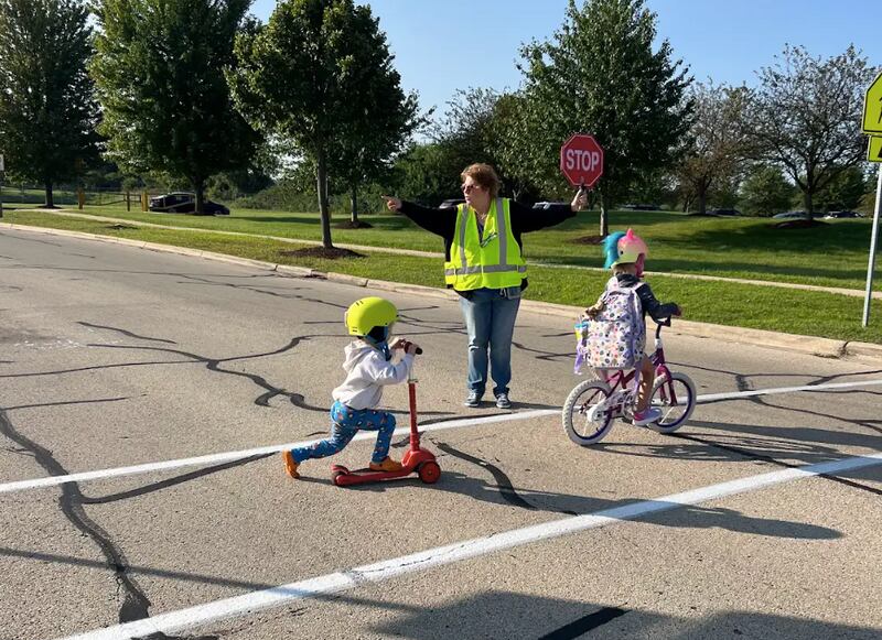 Eight-year crossing guard veteran, Marge Linnane, directs students at Autumn Creek Elementary School in Yorkville safely across the road. Yorkville School District 115 took over crossing guard responsibilities from Yorkville Police this year.
