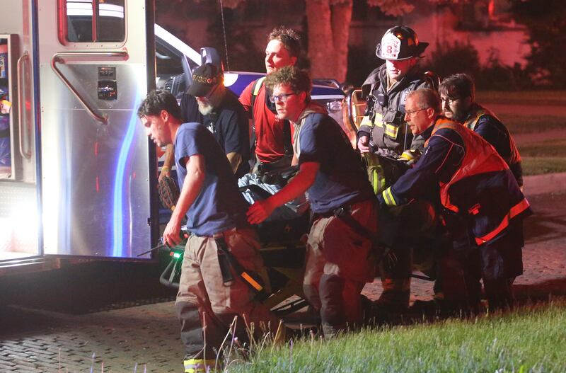 Firefighters bring an injured firefighter to an ambulance during the scene of a structure fire in the 100 block of West Cleveland Street on Thursday, May 15, 2025 in Spring Valley. The fire broke out shortly before 8:30p.m. Fire departments from La Salle Bureau and Putnam Counties responded to the scene. A mutual aid box alarm system (MABAS) call was issued prompting the response.