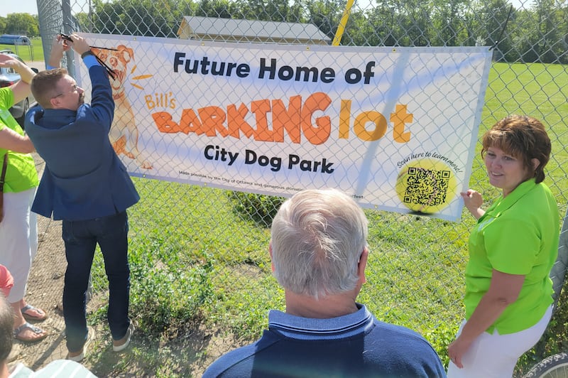 Ottawa Mayor Robb Hasty (left) on Thursday, Aug. 23, 2024, helps to hang the sign labeling the new dog park, "Bill's Barking Lot," in honor of the late Bill Walsh, Sr.