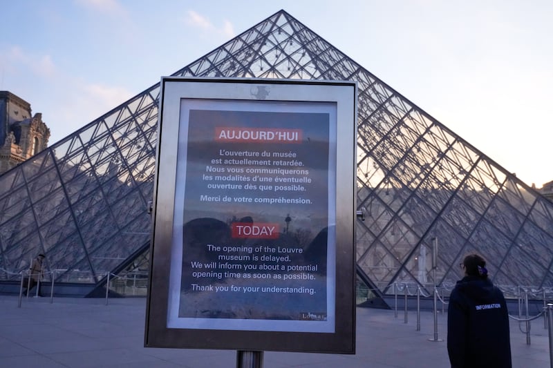 A board advises opening delays outside the pyramid of the Louvre museum as workers at the Louvre will vote to go on strike or continue talks with the government after months of mounting pressure on the world's most visited museum, Monday, Dec. 15, 2025 in Paris. (AP Photo/Michel Euler)