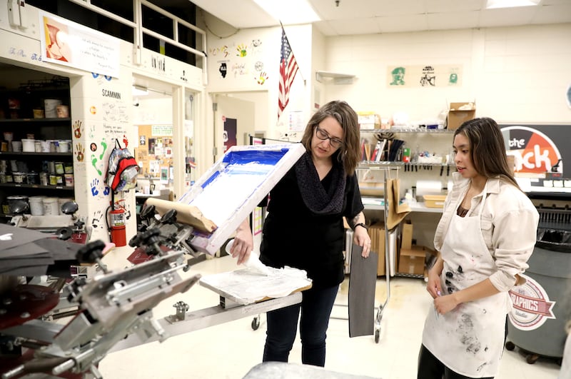 Batavia High School Graphic Arts teacher Kathleen Tieri Ton works on a screen printing with senior Grace Perea.