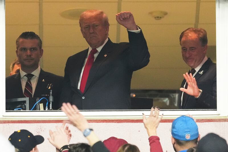 President Donald Trump, center, gestures to the crowd alongside Defense Secretary Pete Hegseth, left, and Washington Commanders owner Josh Harris, as they attend an NFL football game between the Commanders and the Detroit Lions at Northwest Stadium in Landover, Md., Sunday, Nov. 9, 2025. (AP Photo/Jacquelyn Martin)