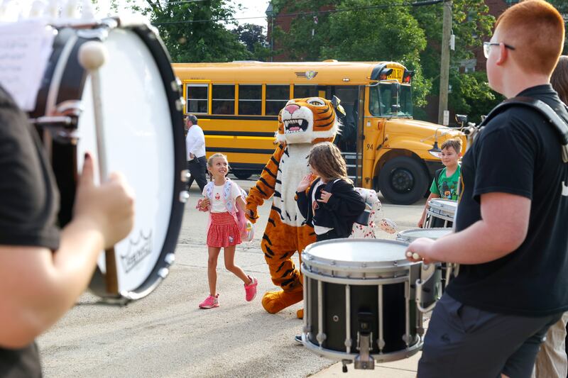 Herscher Intermediate School students are escorted off the bus by the Tigers' mascot past the high school drumline and cheerleaders as they arrived for the first day of school on Aug. 19, 2025.
