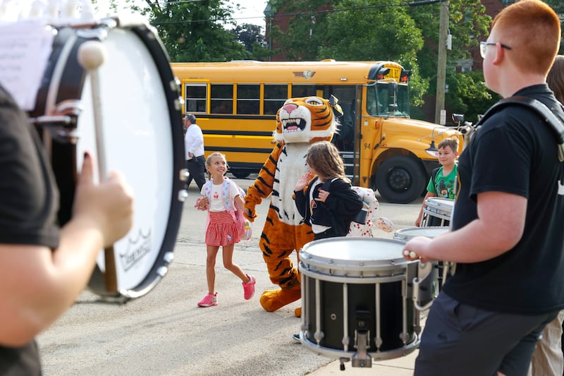 Herscher Intermediate School students are escorted off the bus by the Tigers' mascot past the high school drumline and cheerleaders as they arrived for the first day of school on Aug. 19, 2025.