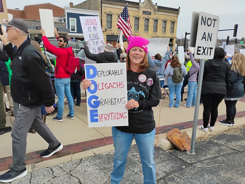 Christine Gear of Batavia, wearing the same pink hat in 2017 when she protested President Trump's first term. Gear, a retired teacher, was among thousands who filled the sidewalks on both sides of the State Street bridge over the Fox River on Saturday to voice their opposition to President Trump and Elon Musk.