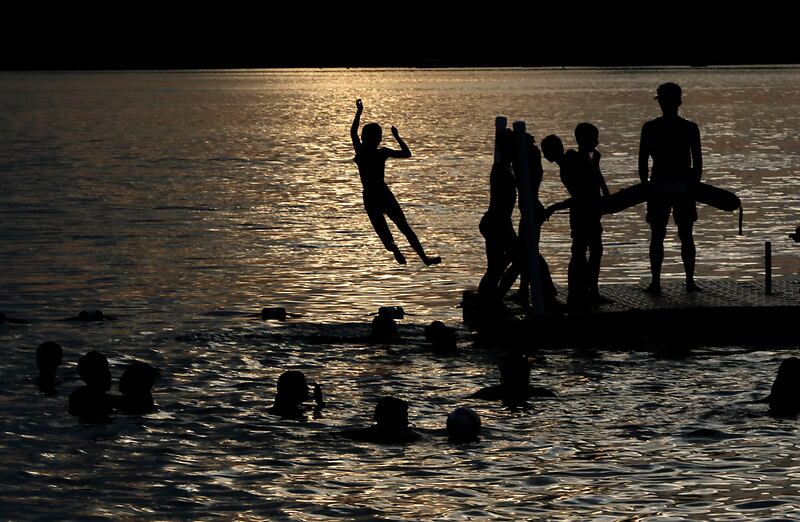 People enjoy the waters of Crystal Lake during the Crystal Lake Park District's Concert in the Park on Tuesday, June 17, 2025, at Main Beach in Crystal Lake. The concert was part of the park district's weekly Tuesday night summer concert series.