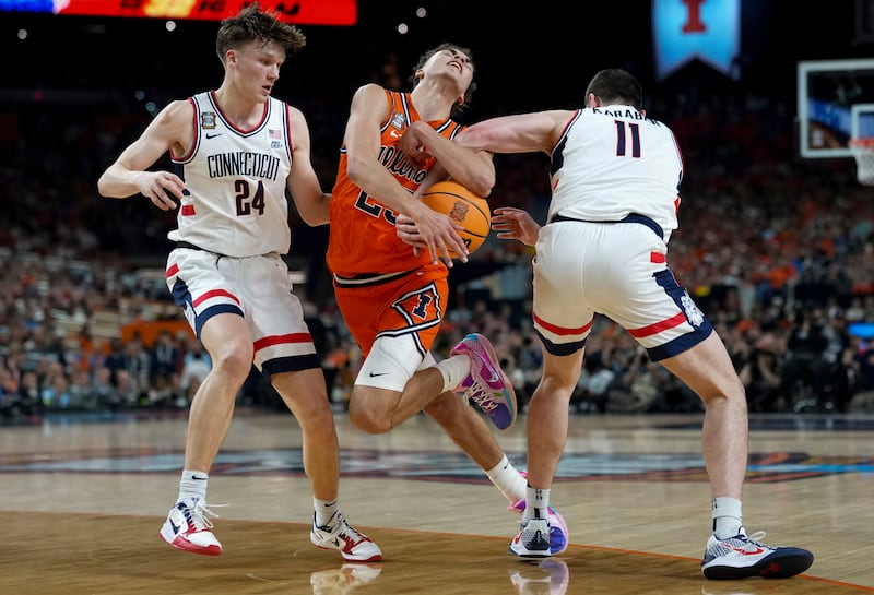 UConn forward Alex Karaban (11) steals the ball away from Illinois guard Keaton Wagler (23) as guard Braylon Mullins (24) looks on during the first half of an NCAA college basketball tournament semifinal game at the Final Four, Saturday, April 4, 2026, in Indianapolis. (AP Photo/Abbie Parr)