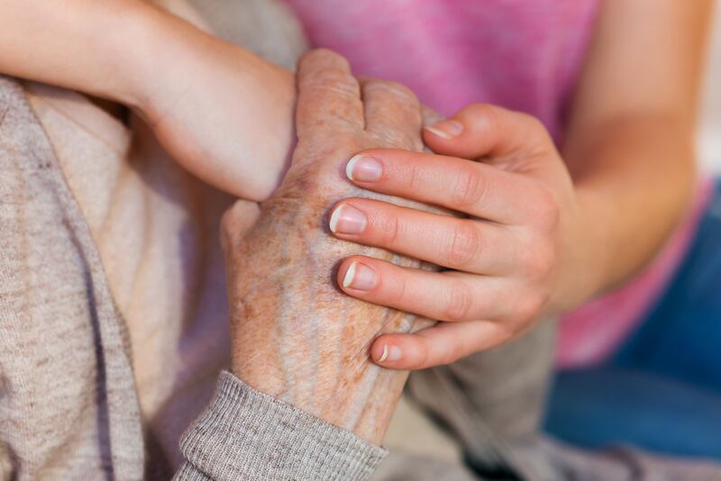 Unrecognizable grandmother and her granddaughter holding hands.