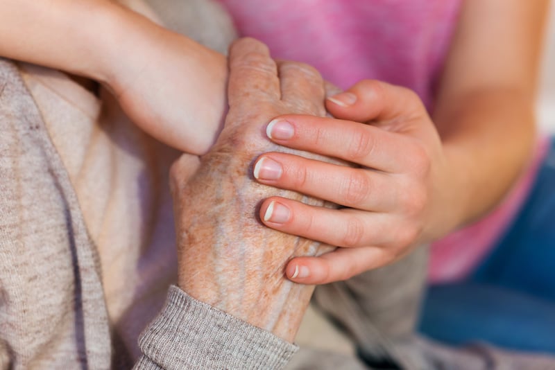 Unrecognizable grandmother and her granddaughter holding hands.