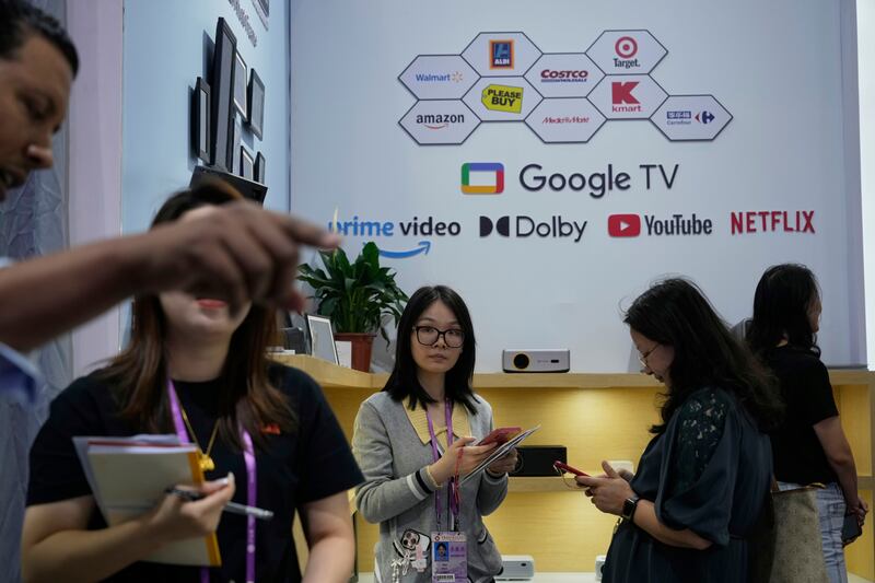Sales rep promote projectors at the 137th Canton Fair in Guangzhou in southern China's Guangdong province on Tuesday, April 15, 2025. (AP Photo/Ng Han Guan)