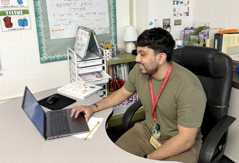 Crystal Lake District 47 Dual Language teacher Manuel Gonzalez reads on his computer with his class book from elementary school and his class book from this year April 23, 2025.