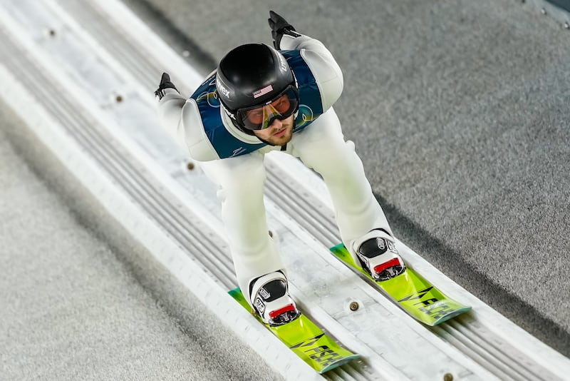 Kevin Bickner, of the United States, goes down the ramp during his trial jump of the ski jumping men's normal hill individual at the 2026 Winter Olympics, in Predazzo, Italy, Monday, Feb. 9, 2026. (AP Photo/Matthias Schrader)