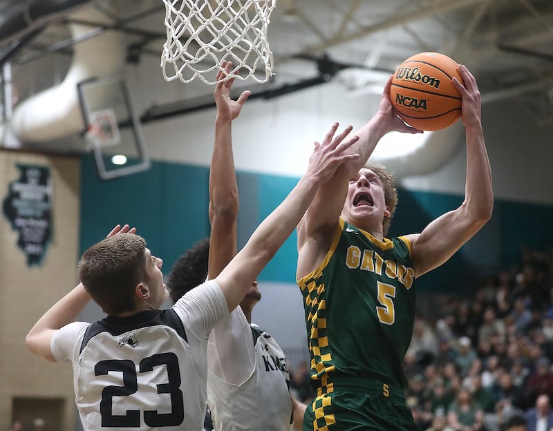 Crystal Lake South's Carson Trivellini (right) drives to the basket agaisnt Kaneland's Connor Kimme (left) and Evan Frieders (center) during the IHSA Class 3A Woodstock North Sectional final basketball game on Friday, March 6, 2026, at Woodstock North High School.