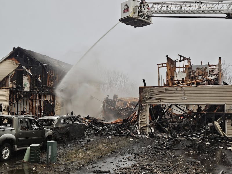 Crews use a fire hose from the DeKalb Fire Department's ladder truck to battle a multi-home fire in the early morning hours on Sunday, March 16, 2025, in the 200 block of Market Street in the Riverbend Subdivision in Genoa.