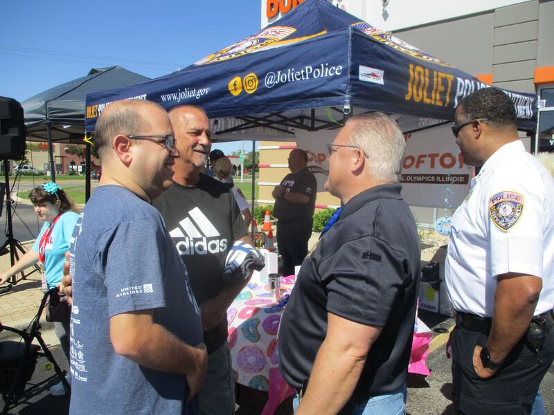 Joliet Police Chief William Evans (right) talks with Jim Kasper (middle), of Shorewood and his son, Anthony Kasper, a former Special Olympics athlete, during the Cop on a Rooftop event on Friday outside the Dunkin' at 3011 Plainfield Road in Joliet. May 16, 2025