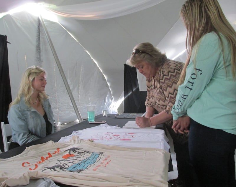 A customer signs up for a custom-made T-shirt Wednesday, May 17, 2023, at Streator High School student Alexandra Austin's Coastline T-Shirts business during the Streator Area CEO Trade Show at the Eastwood.