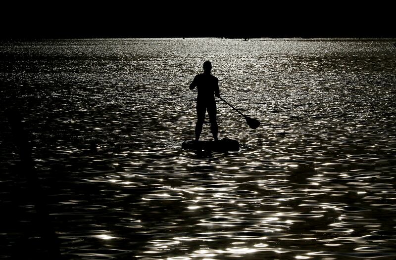 A paddle boarder paddles towards Main Beach for Crystal Lake Park District's Concert in the Park on Tuesday, June 17, 2025, at Main Beach in Crystal Lake. The concert was part of the park district's weekly Tuesday night summer concert series.
