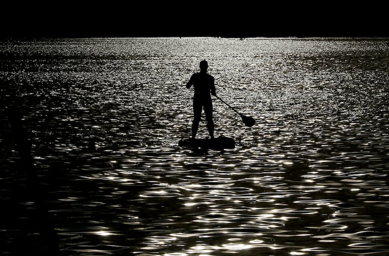 A paddle boarder paddles towards Main Beach for Crystal Lake Park District's Concert in the Park on Tuesday, June 17, 2025, at Main Beach in Crystal Lake. The concert was part of the park district's weekly Tuesday night summer concert series.